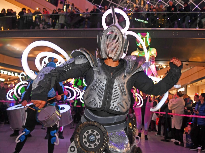 Illuminated drummers and dancers swirl around the towering IOLA 2.0, filling Trinity Leeds with light, energy, and infectious beats.