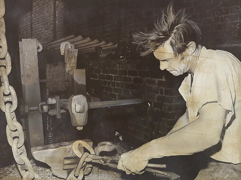 Tongs gripped tightly as sparks fly, chainmaker John Brian Williams works over the hearth at Bloomer & Sons Ltd in Quarry Bank in February 1974. With two decades of dedicated craftsmanship under his belt, Williams is captured shaping heavy cable chain link by link using traditional Black Country forge methods that demanded immense strength and pinpoint precision. Small-scale chain shops like Bloomer's kept the area's proud metalworking heritage alive, forging durable industrial and marine chains trusted across Britain and the world. Did you or someone in your family work in the Quarry Bank chain trade, or do you remember Bloomer & Sons back in 1974?