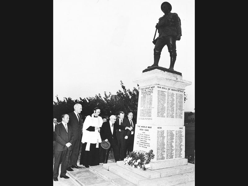 Clergy and brewery stalwarts gather at the base of the Springfield Brewery war memorial during a moving rededication service in July 1974. First erected after the First World War in the brewery yard of Butler’s in Springfield, Wolverhampton, the statue had originally been shifted when horse-drawn drays gave way to motor lorries—and was forced to move once again as modern commercial vehicles grew even larger. Relocated to the peaceful grounds of the firm’s social club, the monument was rededicated by the Reverend Roy Davies, Vicar of St Stephen’s Church. Arthur Fowler is seen pointing out fallen colleagues' names on the roll of honour, joined by social club chairman Bill Werton, Walter Scott, and Harry Cohen. Did you work at Butler's Springfield Brewery or attend the memorial's rededication service back in the summer of 1974?
